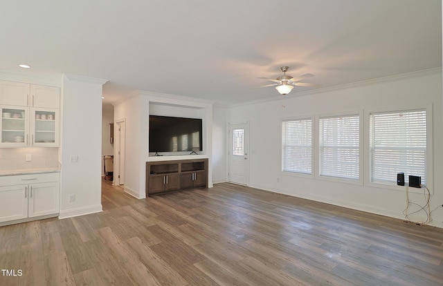 unfurnished living room with ceiling fan, crown molding, and light wood-type flooring