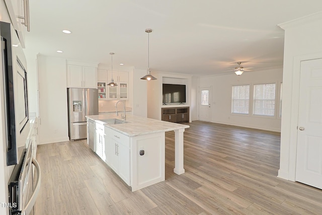 kitchen with ceiling fan, stainless steel appliances, decorative light fixtures, a kitchen island with sink, and white cabinets