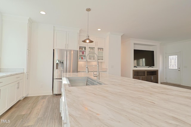 kitchen with light wood-type flooring, sink, white cabinets, stainless steel fridge with ice dispenser, and hanging light fixtures