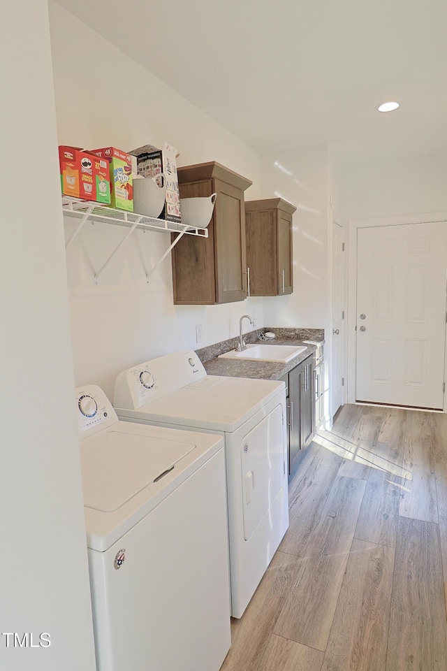 laundry area featuring sink, washer and dryer, and light wood-type flooring