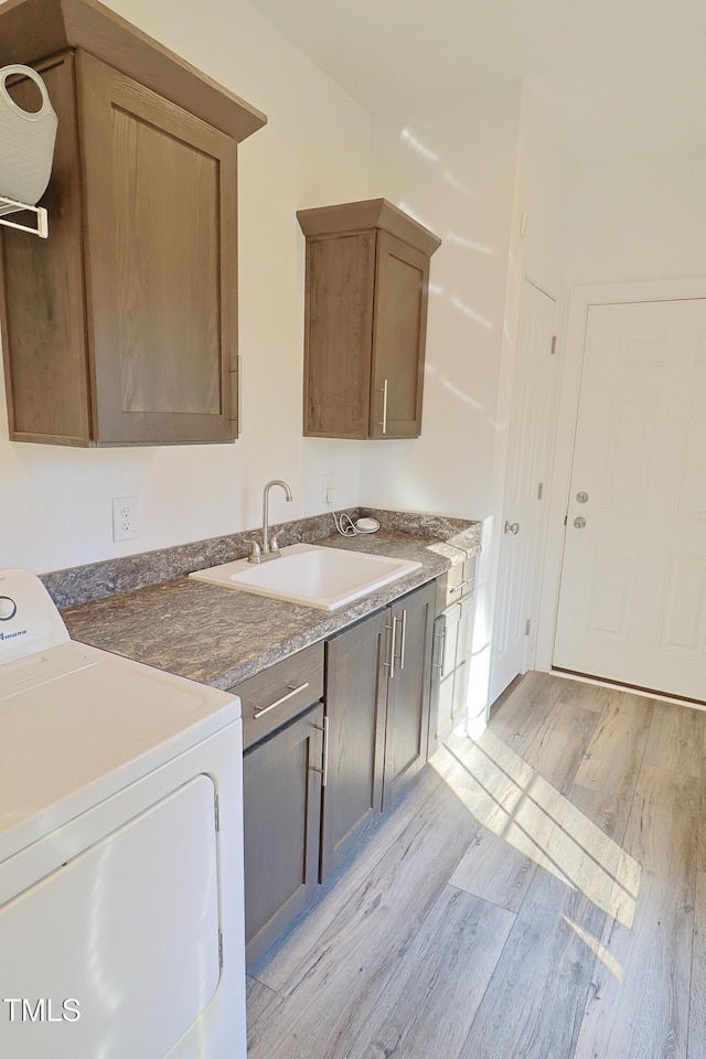 kitchen featuring washer / dryer, sink, and light hardwood / wood-style flooring