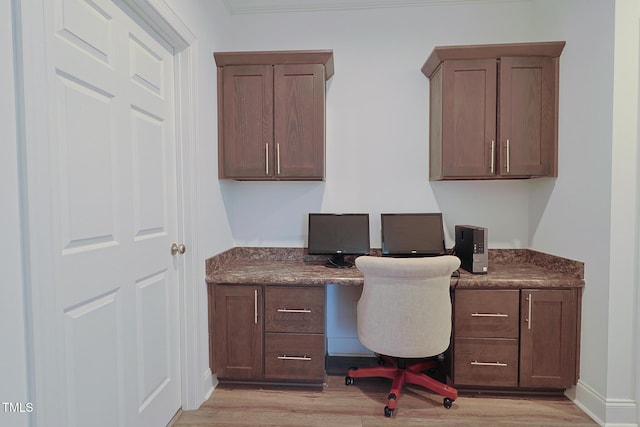 office space with built in desk, ornamental molding, and light hardwood / wood-style flooring