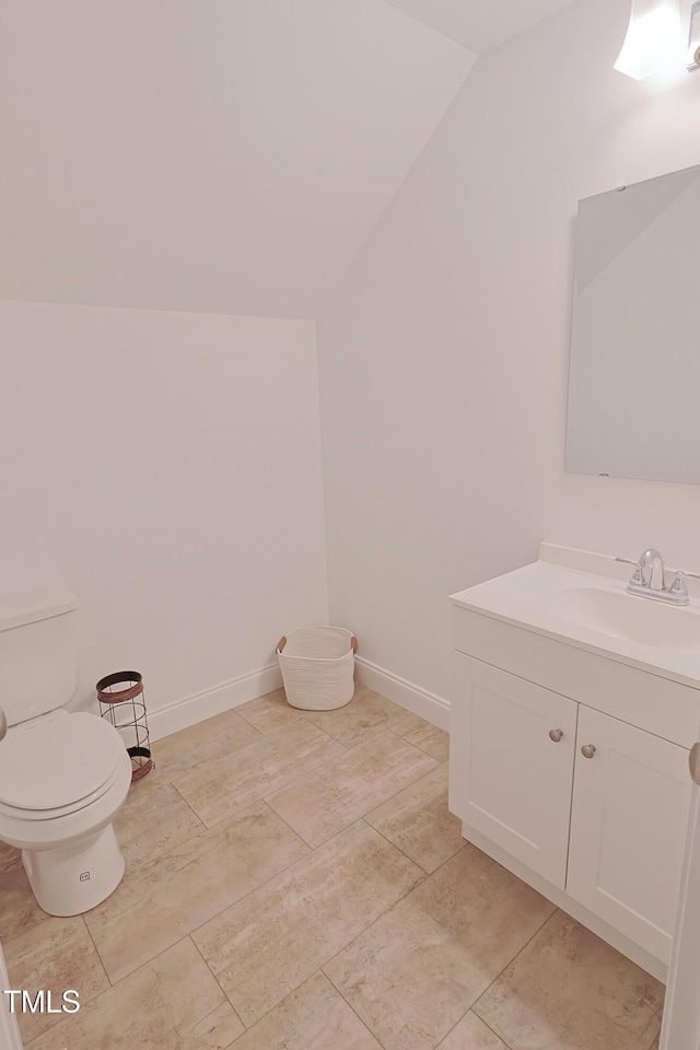 bathroom with vanity, vaulted ceiling, and toilet