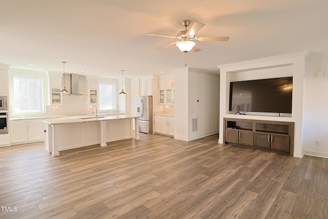 unfurnished living room featuring ceiling fan, crown molding, sink, and light hardwood / wood-style flooring