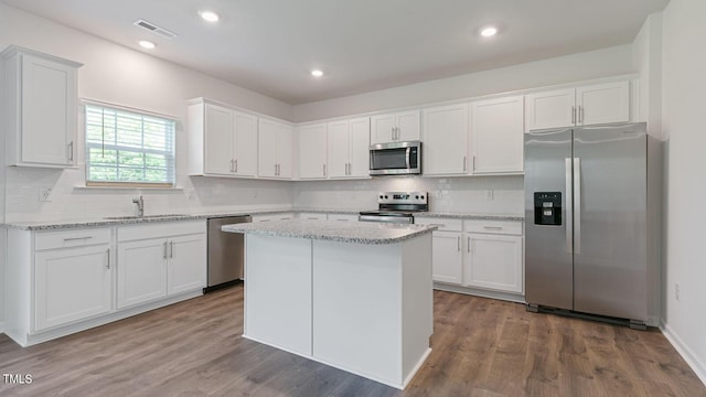 kitchen featuring hardwood / wood-style floors, stainless steel appliances, white cabinetry, and light stone counters