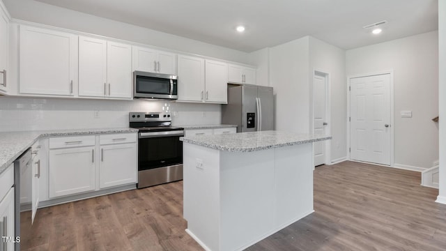 kitchen with white cabinets, a kitchen island, stainless steel appliances, and light hardwood / wood-style flooring