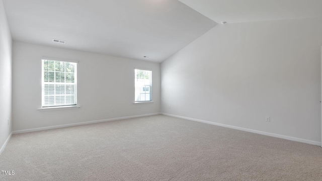 carpeted spare room featuring a wealth of natural light and vaulted ceiling