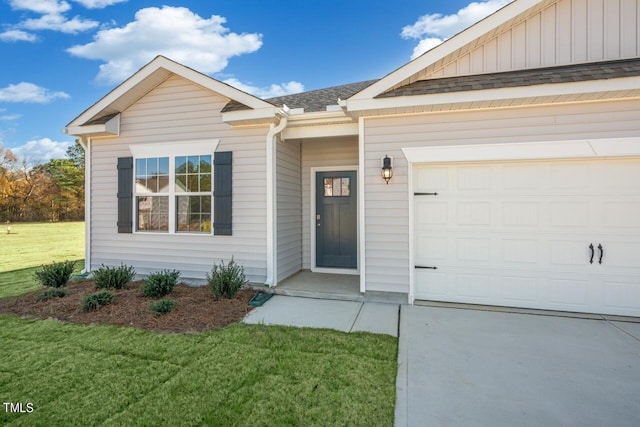 view of exterior entry with a lawn and a garage