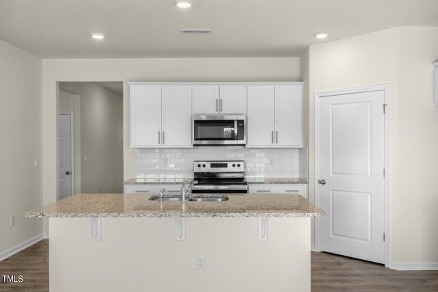 kitchen with white cabinets, appliances with stainless steel finishes, a kitchen island with sink, and sink