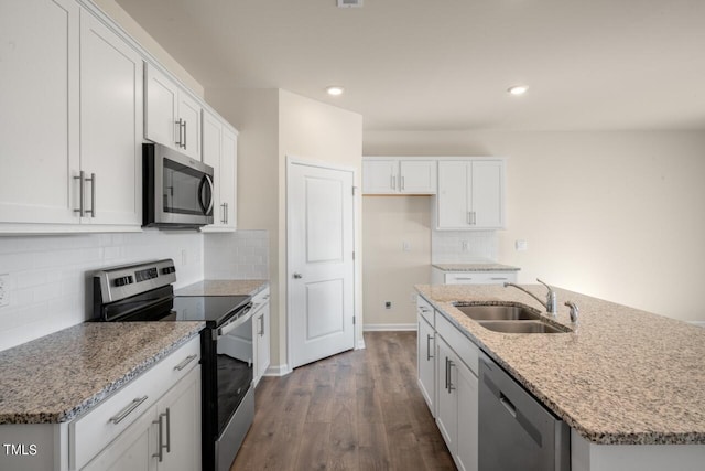 kitchen with appliances with stainless steel finishes, sink, hardwood / wood-style flooring, white cabinets, and an island with sink