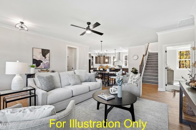 living room featuring ceiling fan with notable chandelier, light wood-type flooring, and crown molding