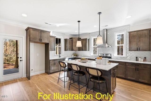 kitchen featuring light hardwood / wood-style flooring, a center island, decorative light fixtures, and wall chimney range hood