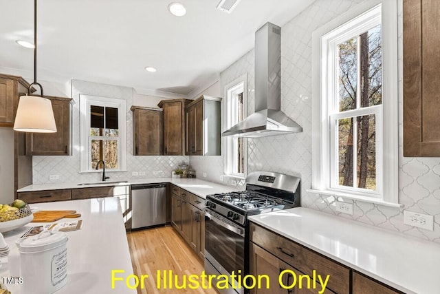 kitchen featuring decorative light fixtures, plenty of natural light, stainless steel appliances, and wall chimney range hood