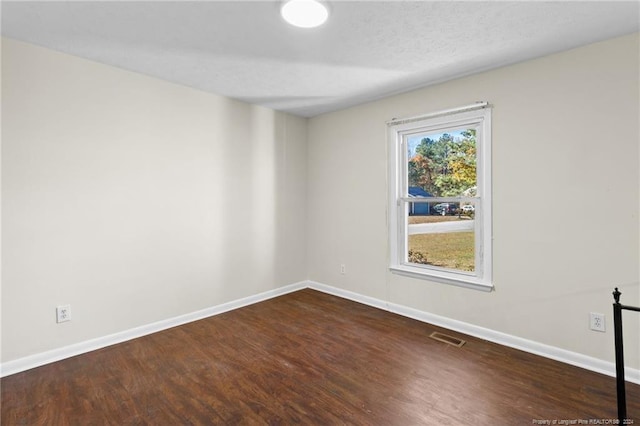 unfurnished room with dark hardwood / wood-style flooring and a textured ceiling