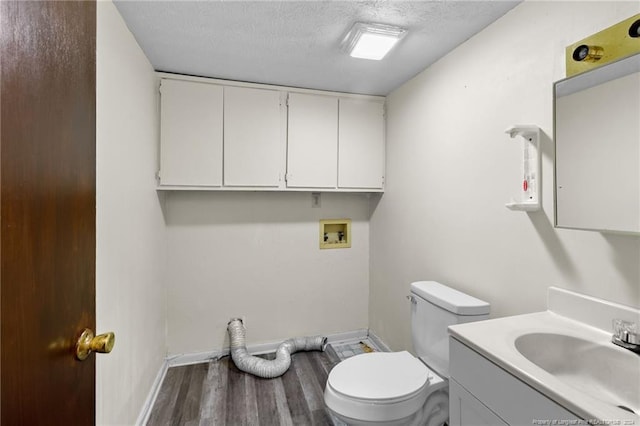 bathroom featuring vanity, toilet, wood-type flooring, and a textured ceiling