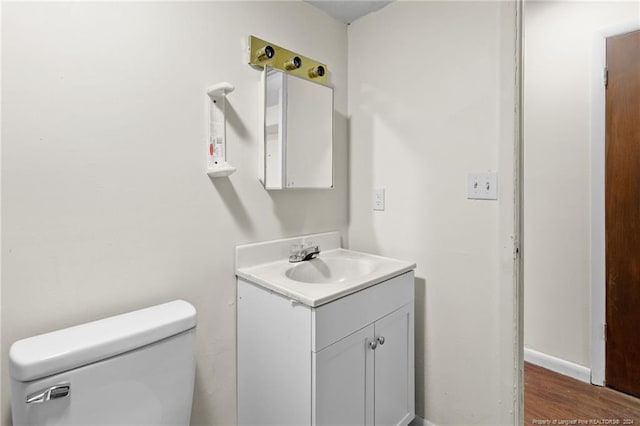 bathroom with hardwood / wood-style floors, vanity, and toilet