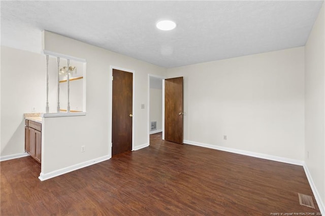 unfurnished bedroom featuring a textured ceiling, connected bathroom, and dark hardwood / wood-style floors