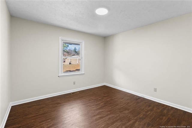 unfurnished room featuring a textured ceiling and dark hardwood / wood-style flooring