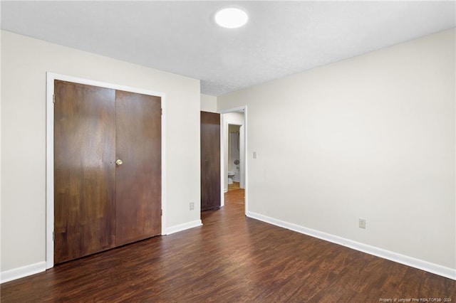 unfurnished bedroom with a closet and dark wood-type flooring