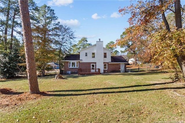 rear view of property featuring a lawn and a deck