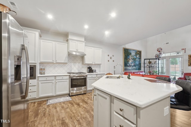 kitchen with stainless steel appliances, white cabinets, an island with sink, and sink