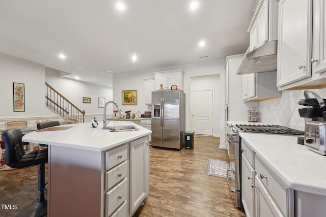 kitchen featuring a center island with sink, light hardwood / wood-style floors, stainless steel appliances, sink, and white cabinetry