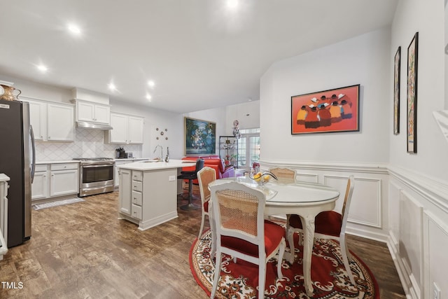 kitchen with sink, white cabinetry, backsplash, a center island with sink, and appliances with stainless steel finishes