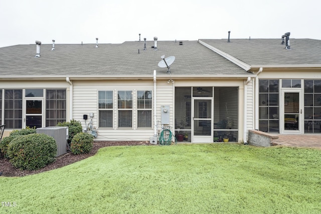 rear view of house featuring a yard, central air condition unit, and a sunroom