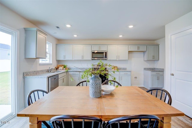 kitchen with appliances with stainless steel finishes, light hardwood / wood-style floors, gray cabinets, and sink