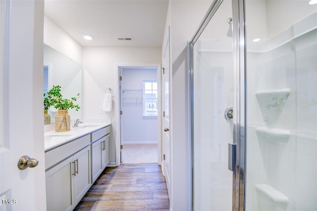 bathroom with walk in shower, vanity, and hardwood / wood-style flooring