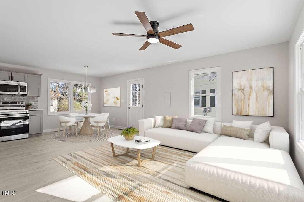 living room featuring ceiling fan with notable chandelier and light hardwood / wood-style floors