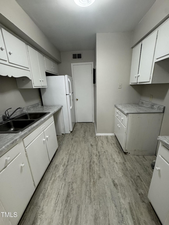 kitchen featuring white cabinetry, sink, white refrigerator, and light wood-type flooring