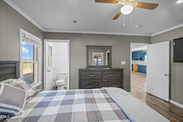 bedroom featuring ceiling fan, wood-type flooring, ornamental molding, and connected bathroom