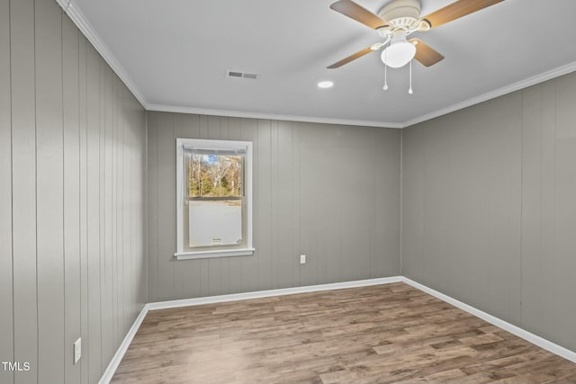 spare room with ceiling fan, wood walls, wood-type flooring, and ornamental molding