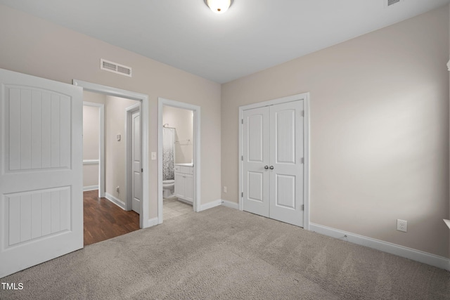 unfurnished bedroom with carpet, ensuite bathroom, and a closet