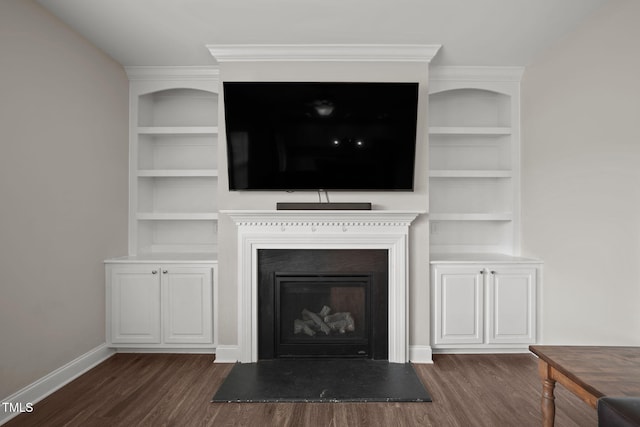 unfurnished living room featuring built in shelves, dark hardwood / wood-style flooring, and ornamental molding