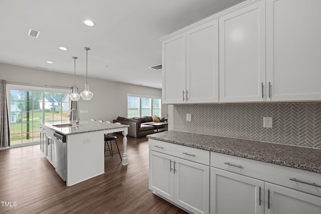 kitchen with light stone countertops, dark hardwood / wood-style flooring, a breakfast bar, pendant lighting, and dishwasher