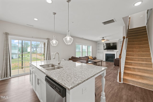 kitchen with pendant lighting, dishwasher, sink, light stone countertops, and white cabinetry