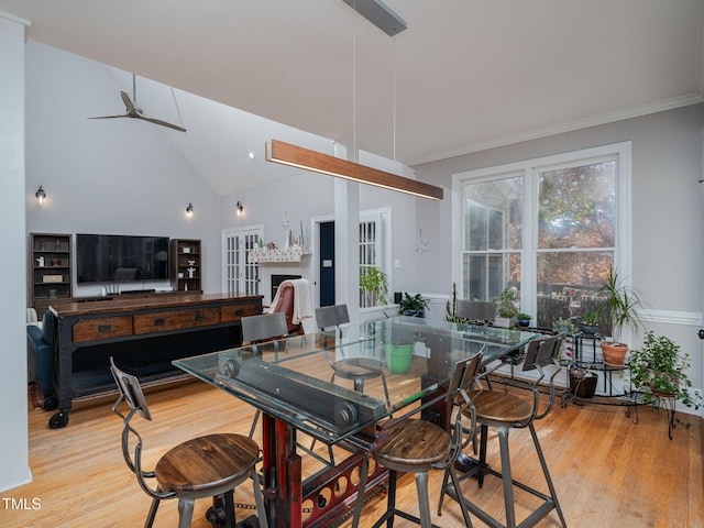 dining room featuring lofted ceiling, light wood-type flooring, a fireplace, and crown molding