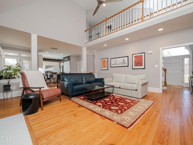 living room featuring light wood-style flooring, recessed lighting, a high ceiling, a ceiling fan, and baseboards