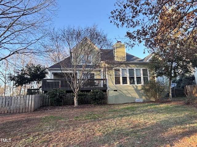 rear view of property with a chimney, fence, a deck, and a yard