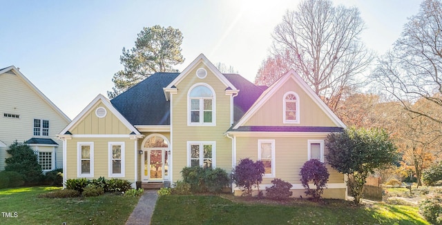 traditional-style house featuring a shingled roof, board and batten siding, and a front yard