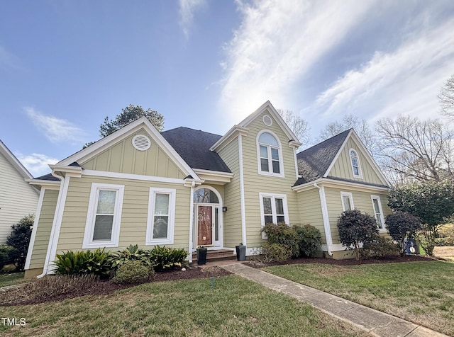 traditional-style house featuring a front lawn, board and batten siding, and roof with shingles