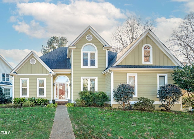 view of front facade with a front yard, board and batten siding, and roof with shingles