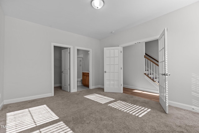 unfurnished bedroom with light carpet, french doors, connected bathroom, and a closet