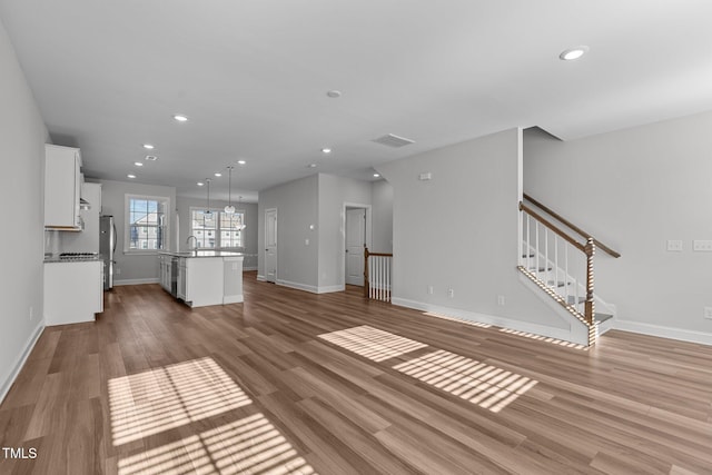 unfurnished living room with sink and light hardwood / wood-style floors