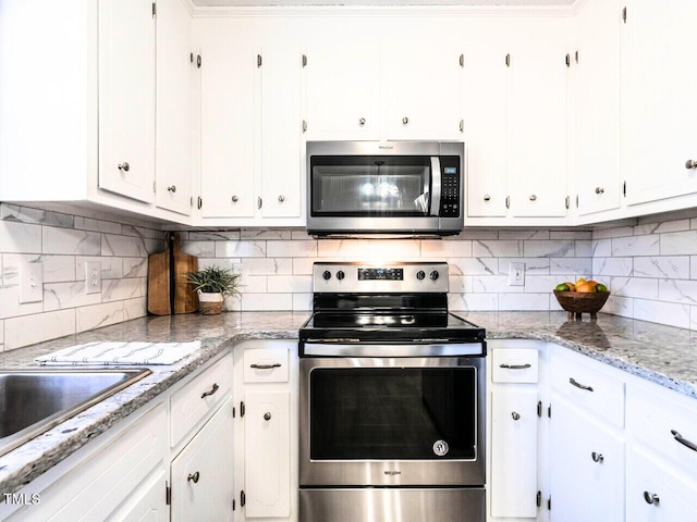 kitchen featuring appliances with stainless steel finishes, light stone countertops, decorative backsplash, and white cabinets