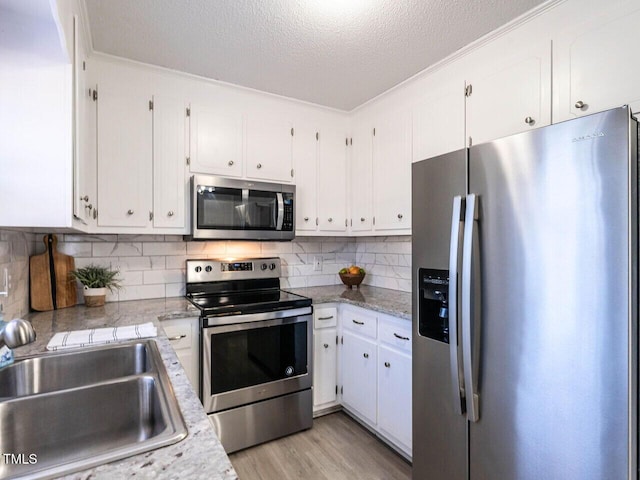 kitchen with sink, white cabinetry, a textured ceiling, stainless steel appliances, and backsplash