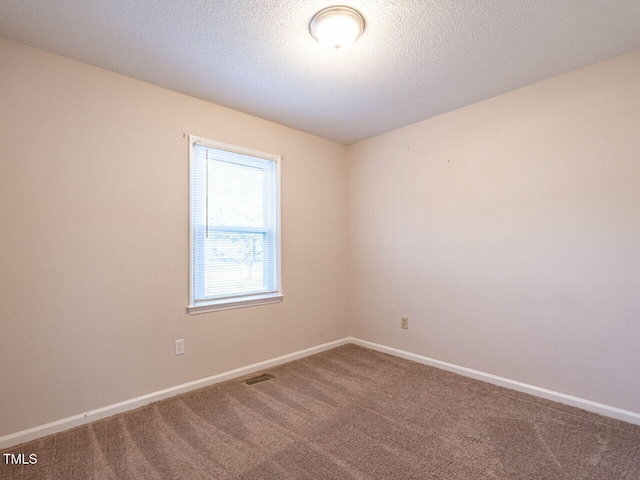 carpeted empty room featuring a textured ceiling