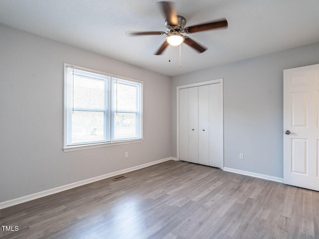 unfurnished bedroom featuring light hardwood / wood-style floors, a closet, and ceiling fan